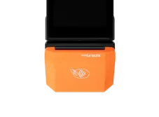Черная онлайн-касса с оранжевой крышкой принтера чеков, на которой расположен знак бесконтактной оплаты